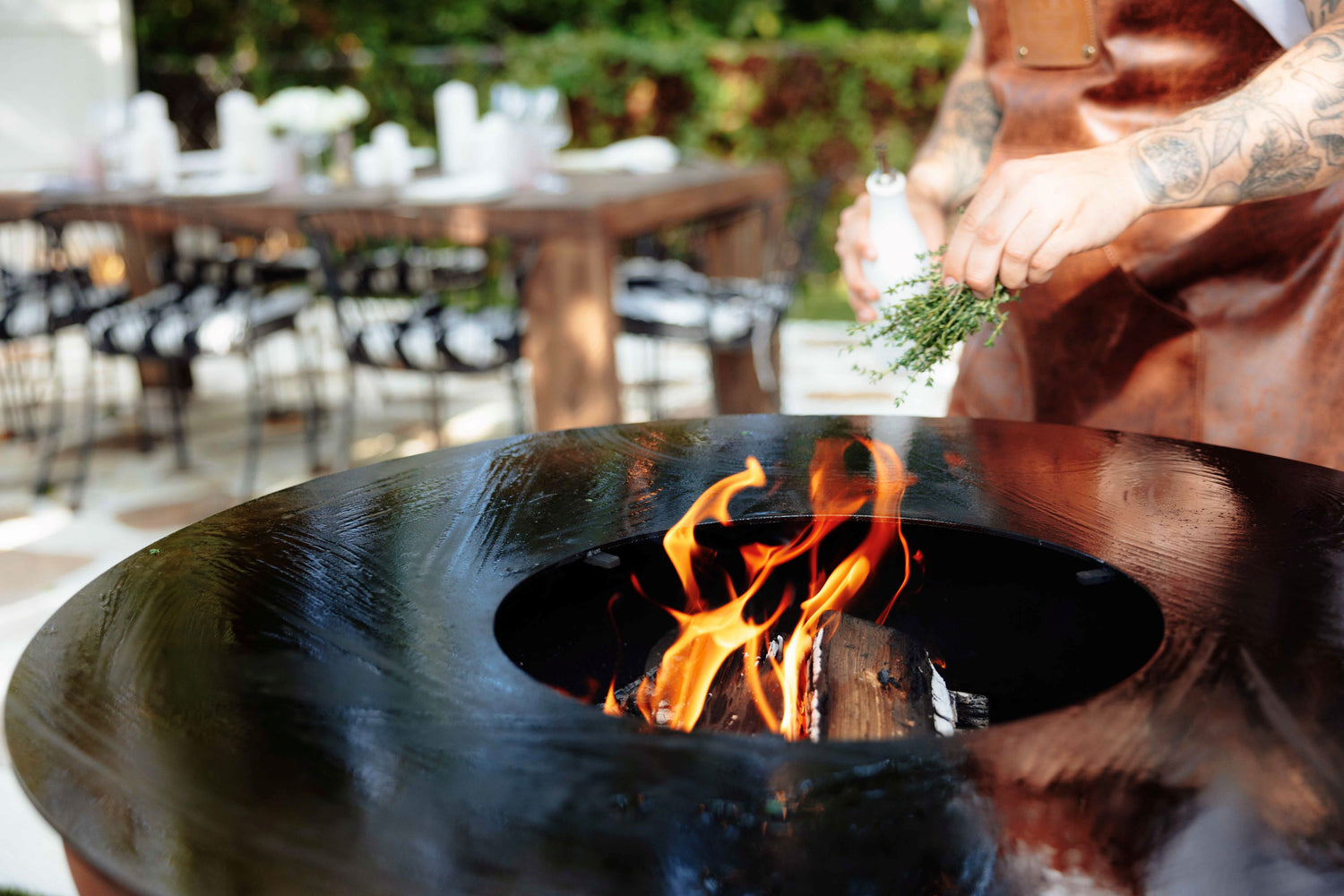 Chef seasoning the multi-zone cooking plate of a Unifire with fresh herbs.