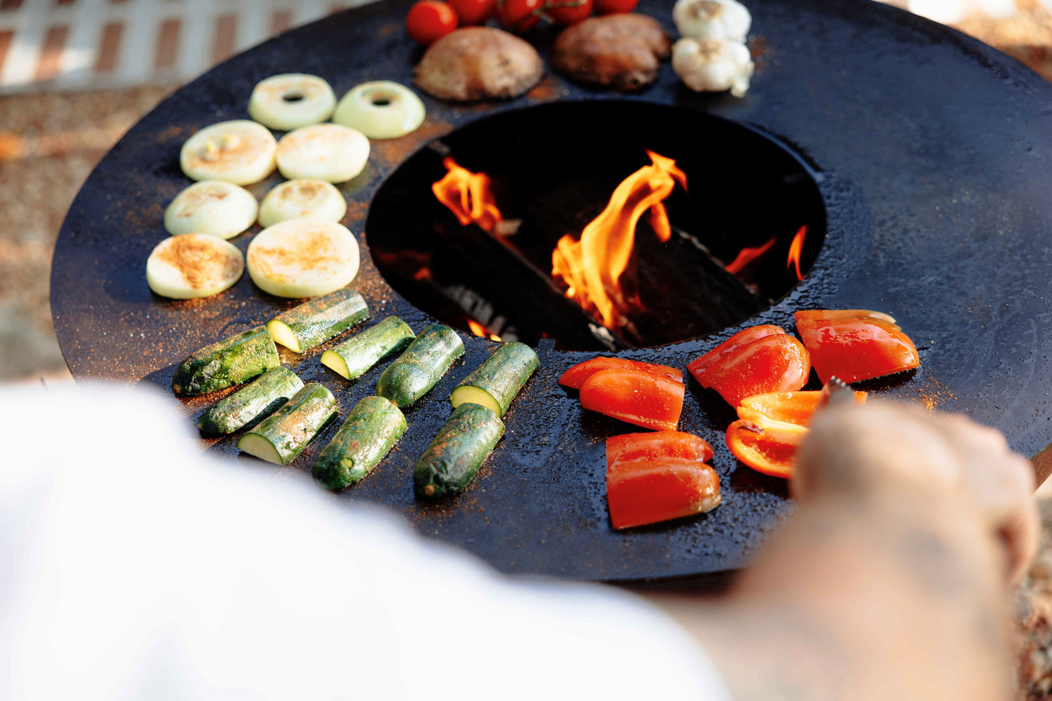 Chef grilling a variety of fresh vegetables on the Unifire cooking plate, showcasing vibrant colors and diverse textures