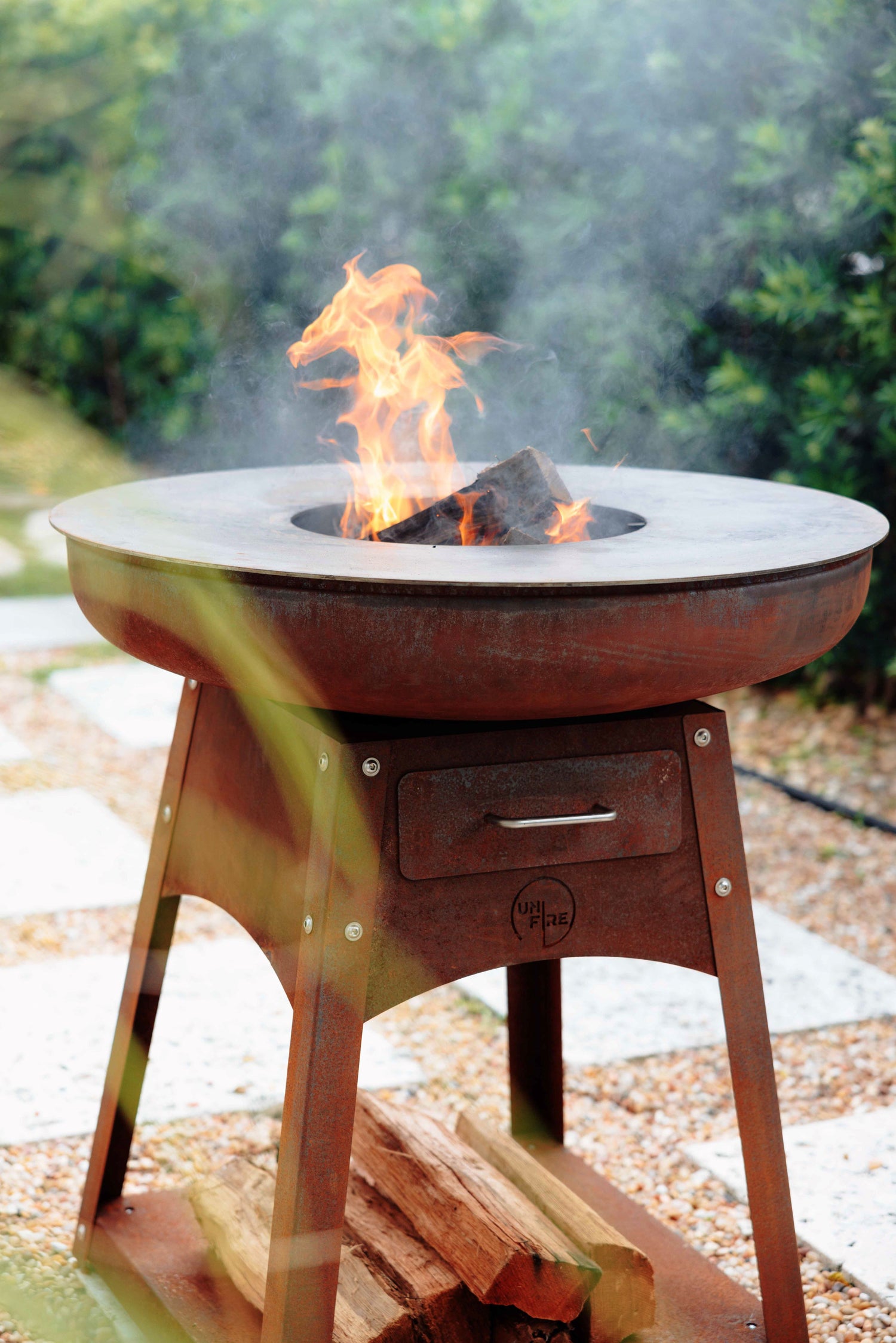 Unifire cooking station with burning wood under a multi-zone cooking plate, heating up for a cookingsession